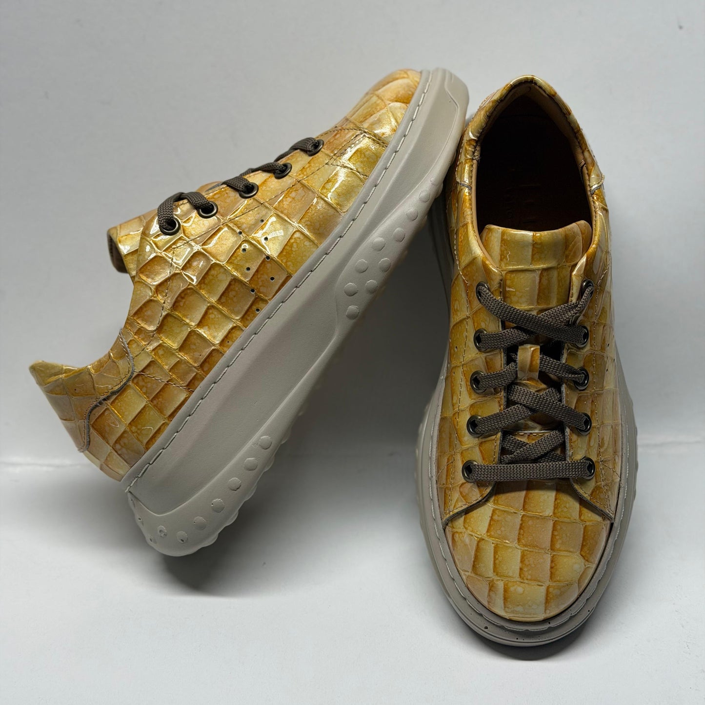 Pair of yellow textured sneakers on a white background