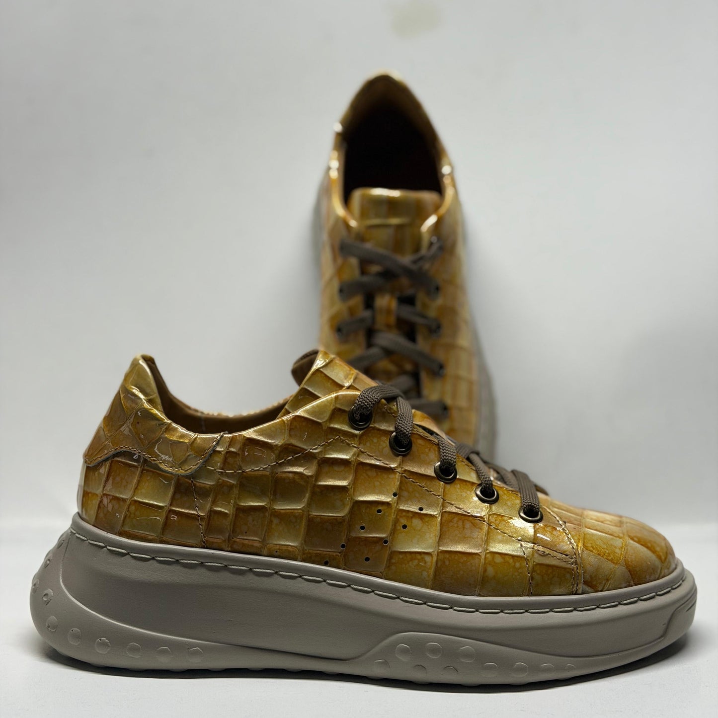Gold textured sneaker with a white sole on a light gray background